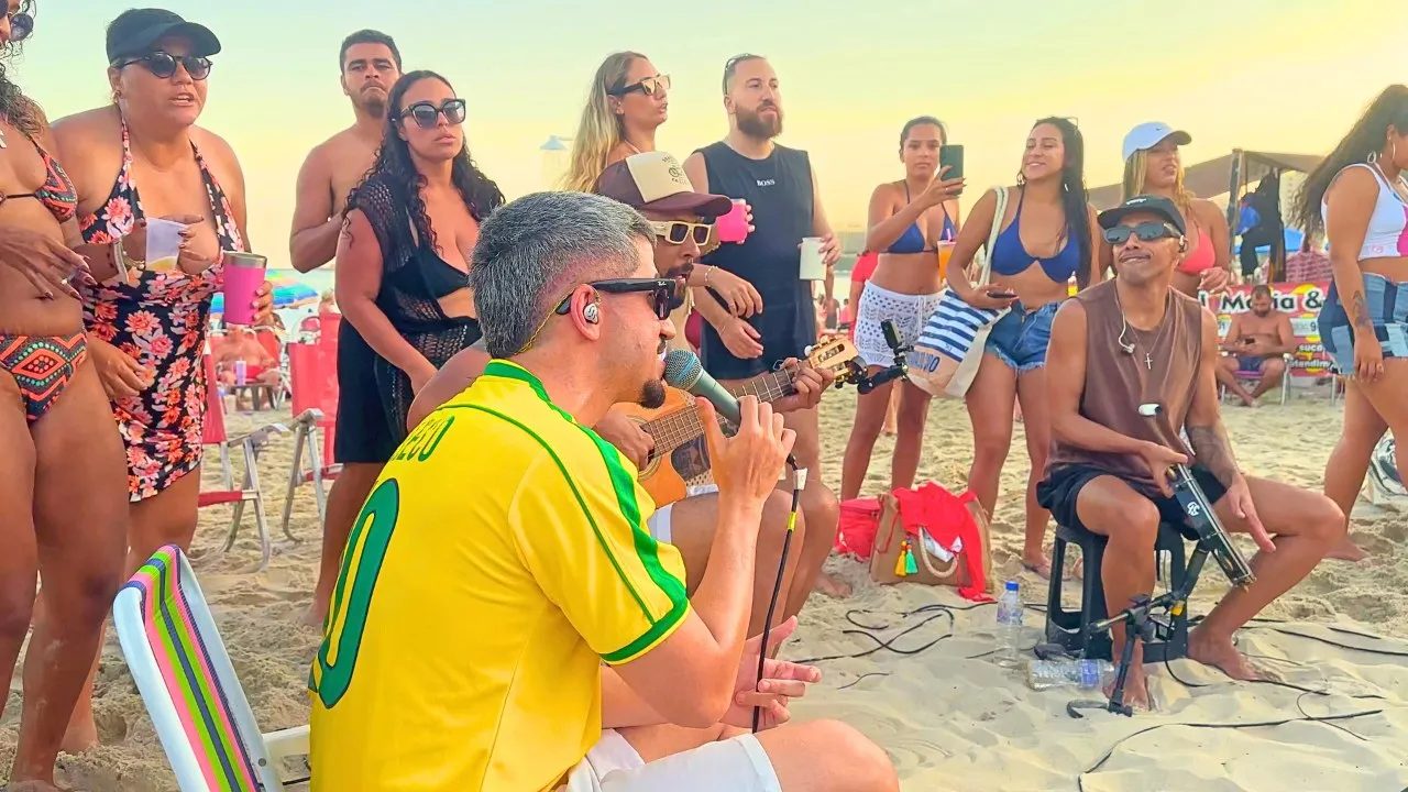 Leleco canta ao microfone durante o pôr do sol, de camisa da seleção brasileira