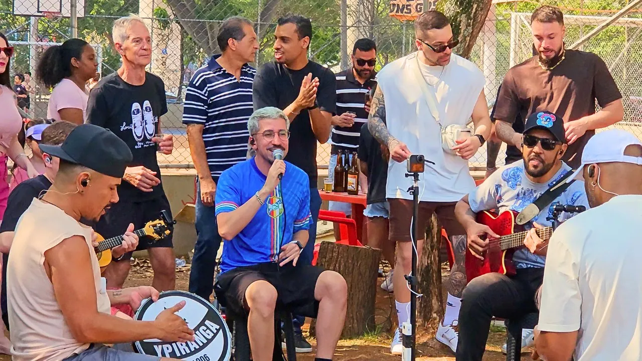 Leleco canta ao microfone em uma roda de pagode em uma quadra ao ar livre
