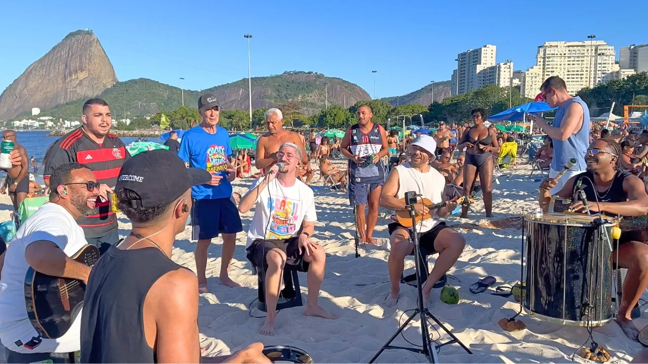 Leleco canta em uma roda de pagode na areia de Copacabana, com o Pão de Açúcar ao fundo