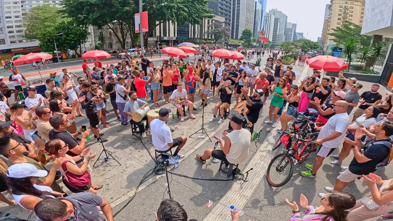 Roda de pagode em um espaço urbano na Avenida Paulista, em São Paulo, com prédios ao fundo